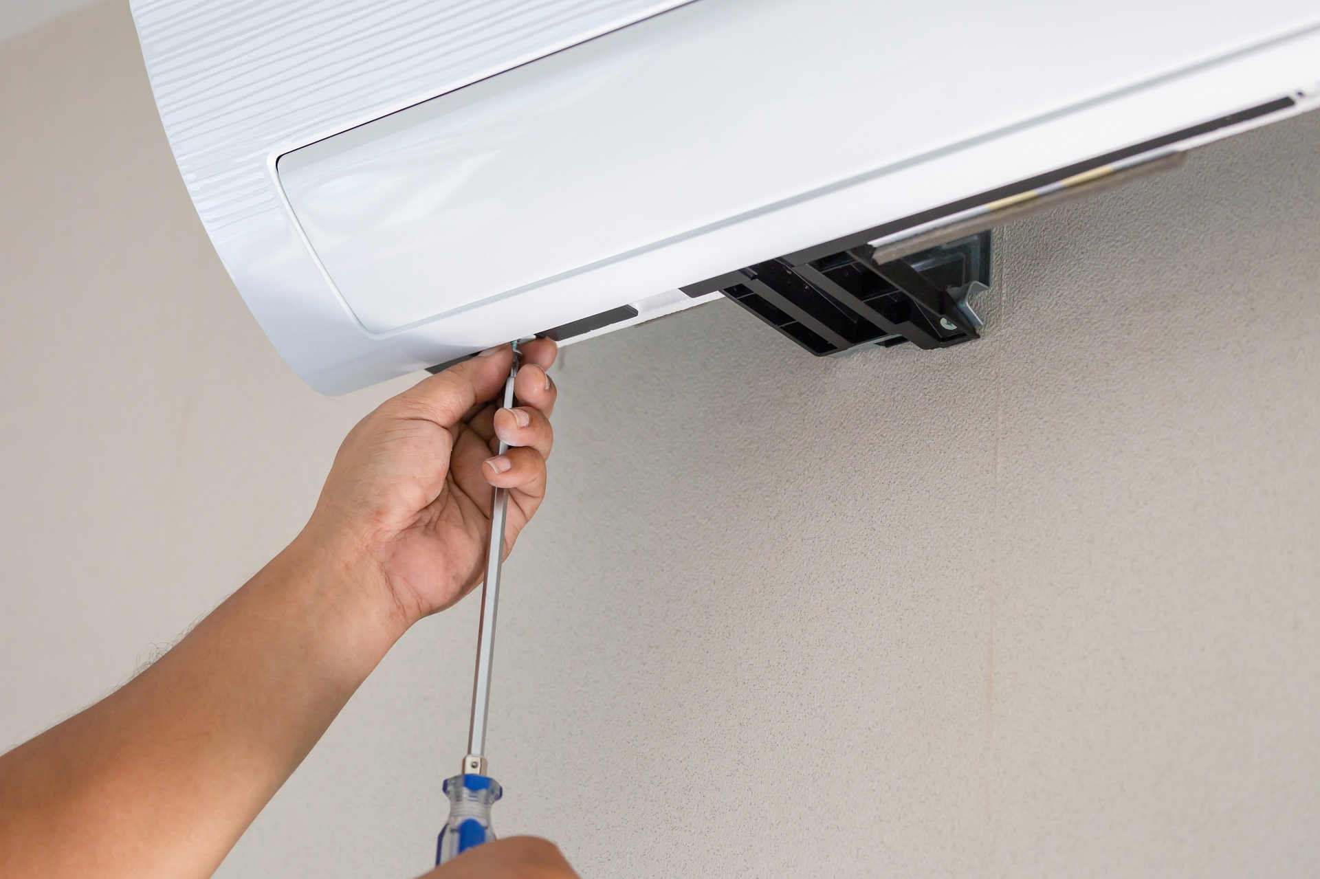 Close up of Male technician hands using a screwdriver fixing a ductless ac unit